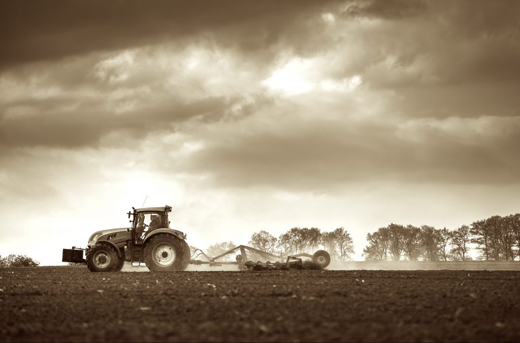 Farming tractor plowing and spraying on field