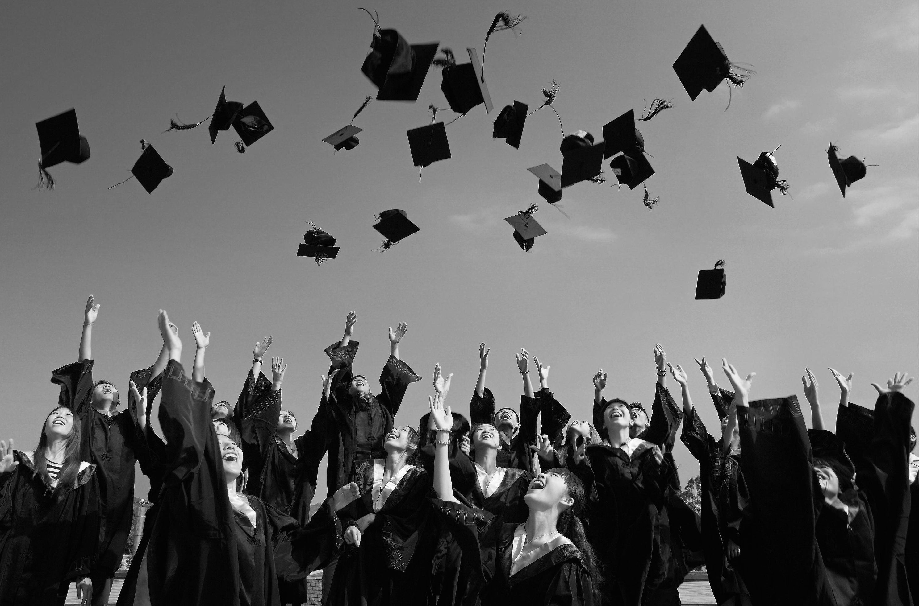 Graduates throwing mortarboards in the air