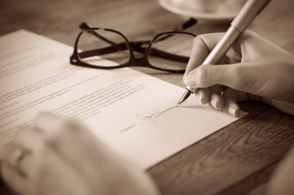 Close up of person signing a contract