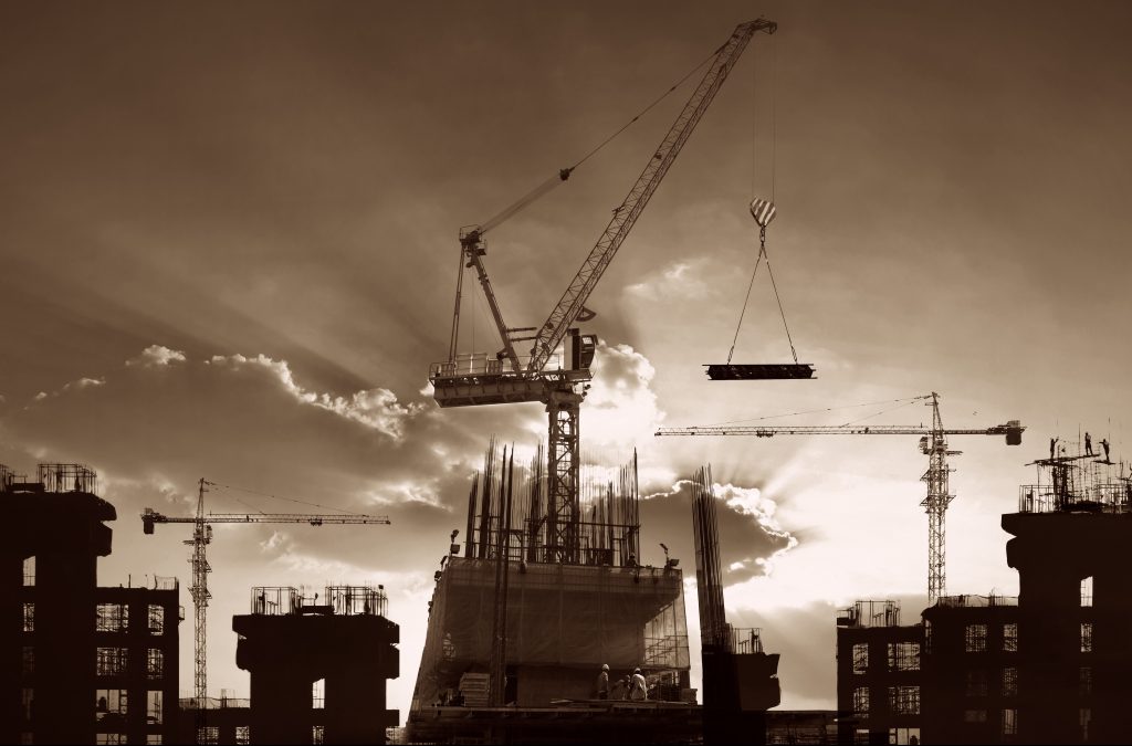Cranes and buildings in construction silhouetted against sunset